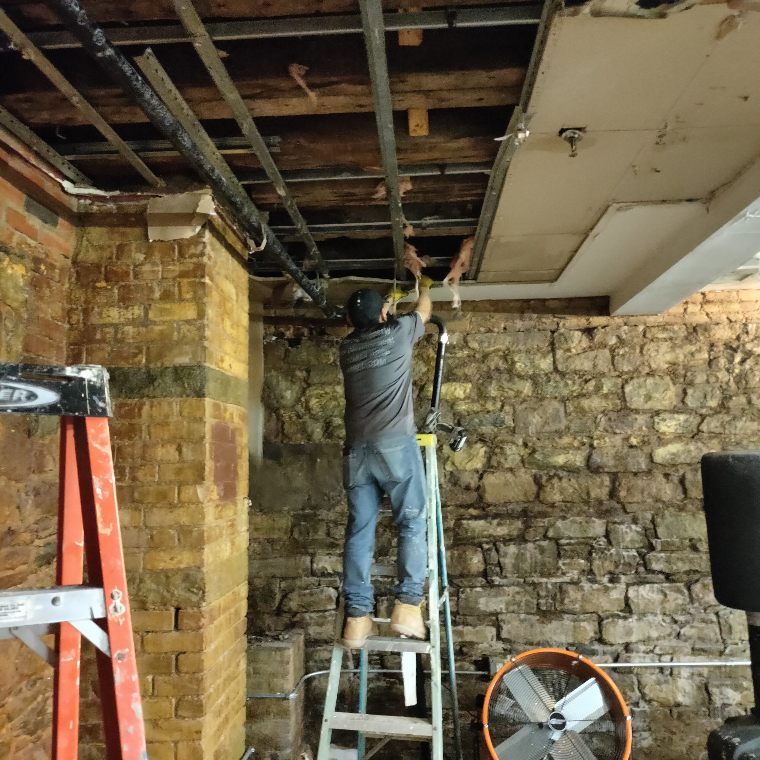 Technician carrying out ceiling-framing repair in a historic below-grade space