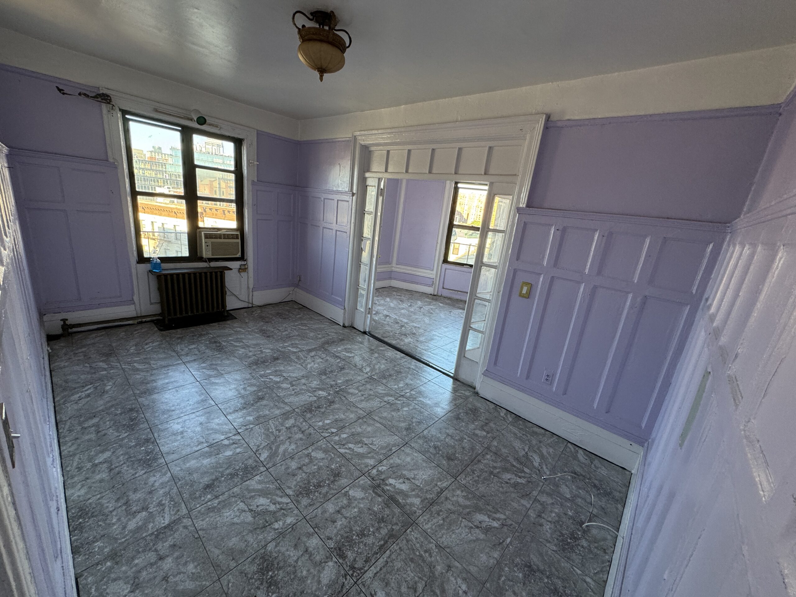 Living room before renovation, with dated flooring and lavender wall color