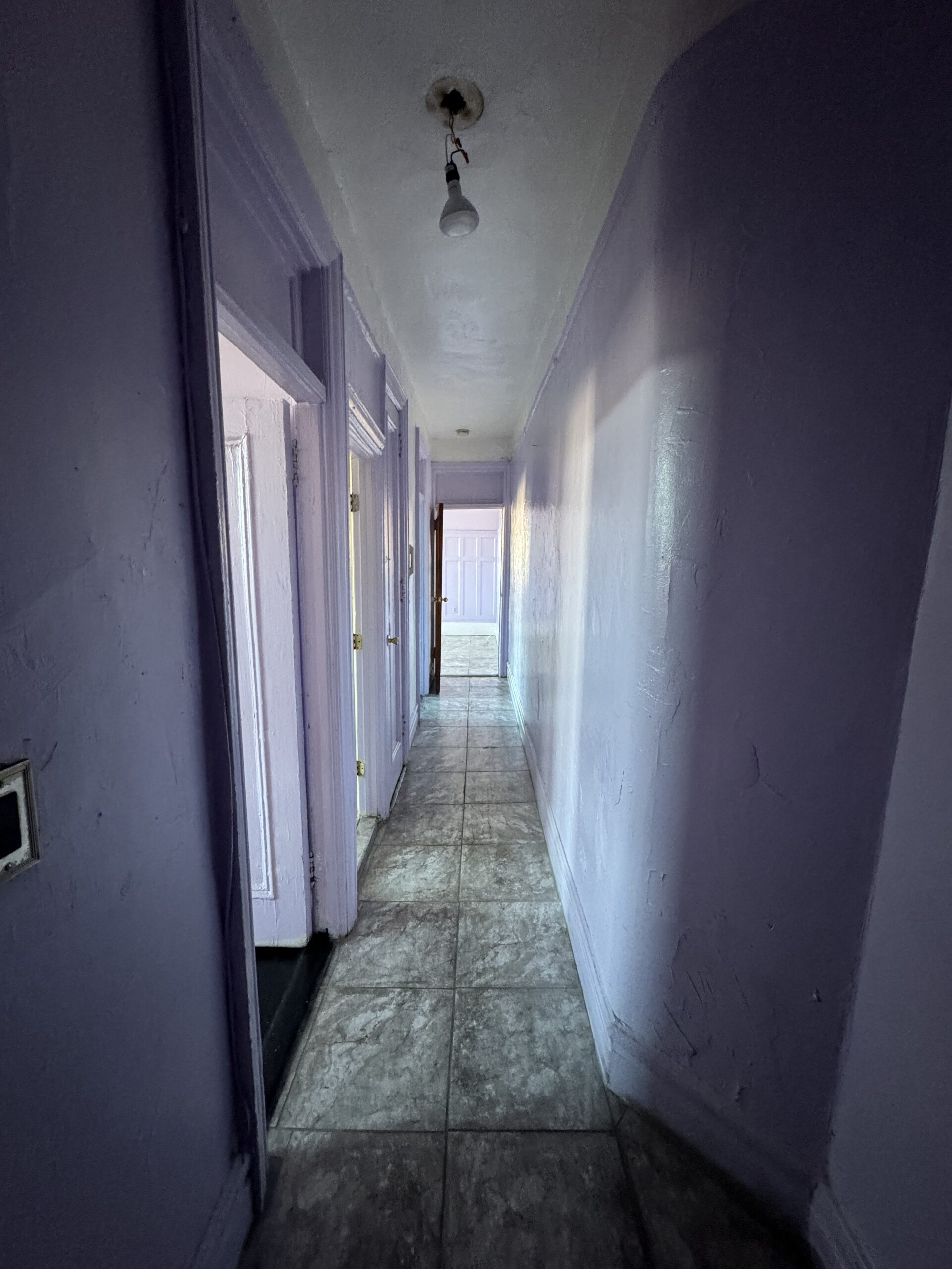 Hallway before renovation, with dated lavender walls and flooring